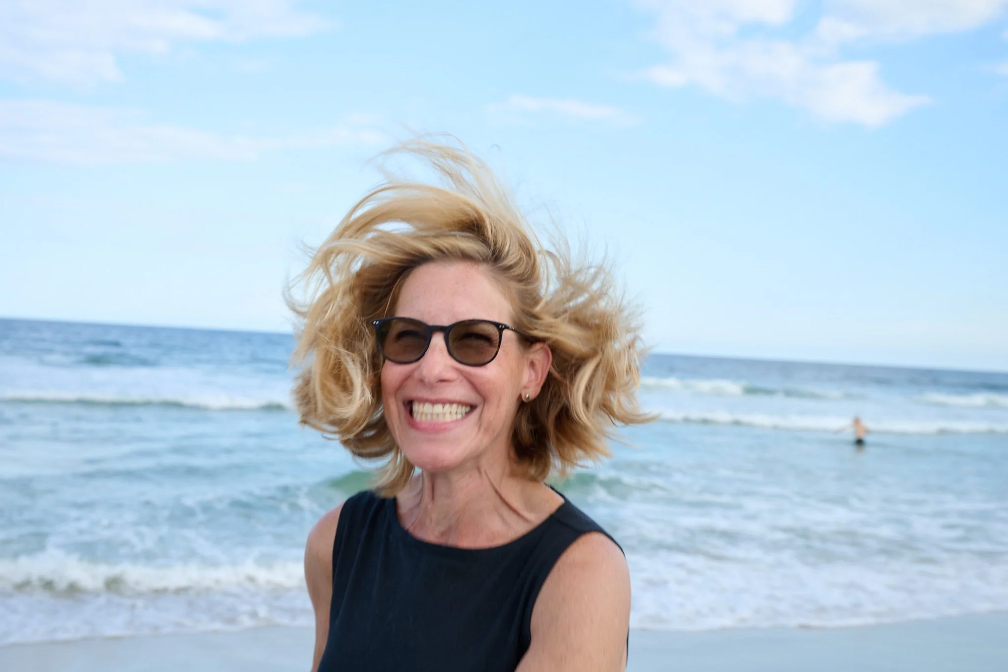 Woman smiles as her hair blows in the wind at Beach Haven on Long Beach Island on the Jersey Shore by family photographer Pamela Einarsen.