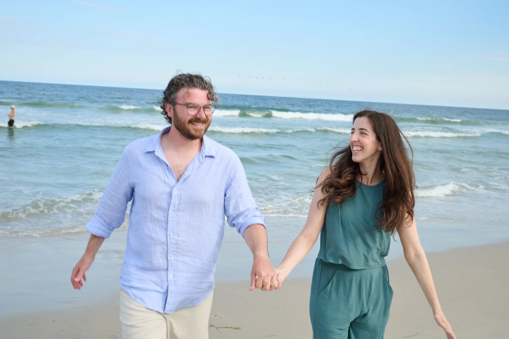 A couple holds hands walking on the beach on the Jersey Shore with family photographer Pamela Einarsen.