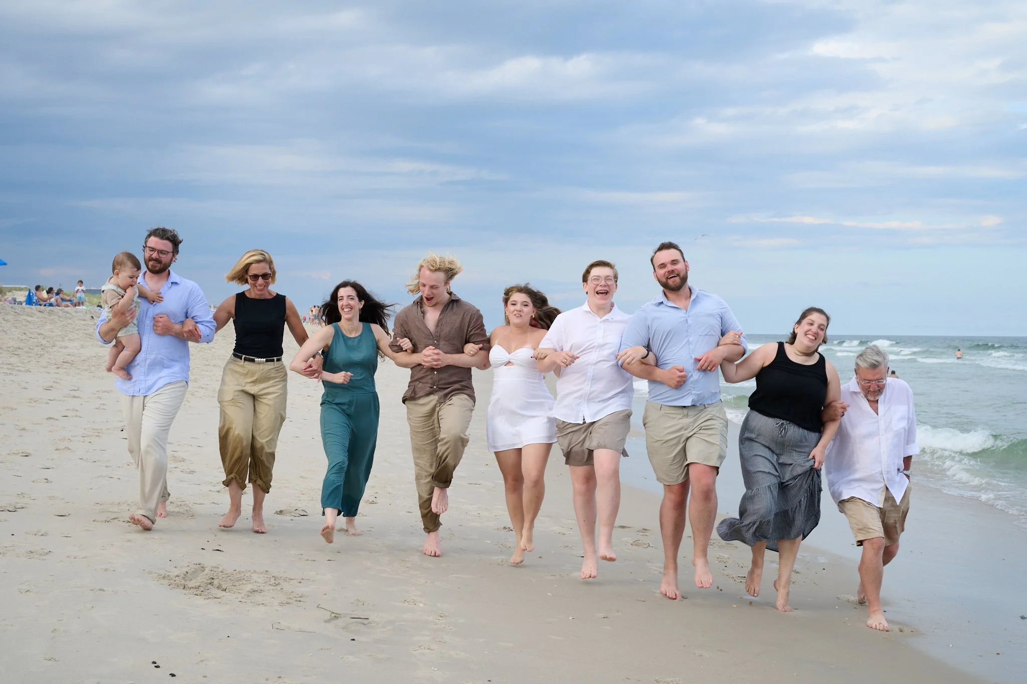Extended family skips on the beach laughing on Long Beach Island with photographer Pamela Einarsen.
