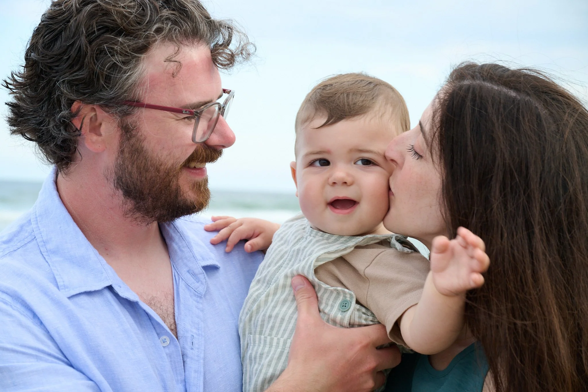 A couple cuddles their baby on the beach on Long Beach Island, NJ with family photographer Pamela Einarsen. 