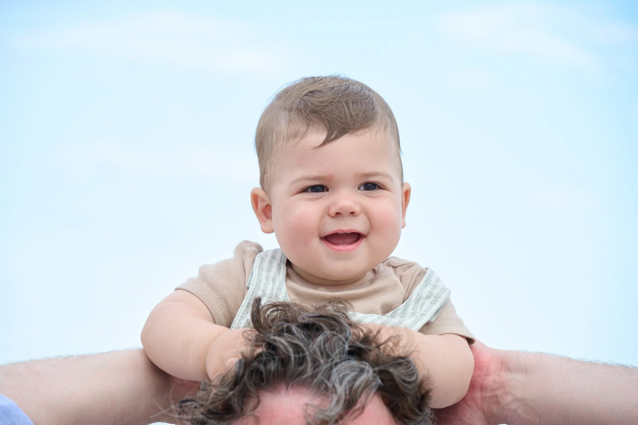 Baby smiles on his father’s shoulders with family photographer Pamela Einarsen.