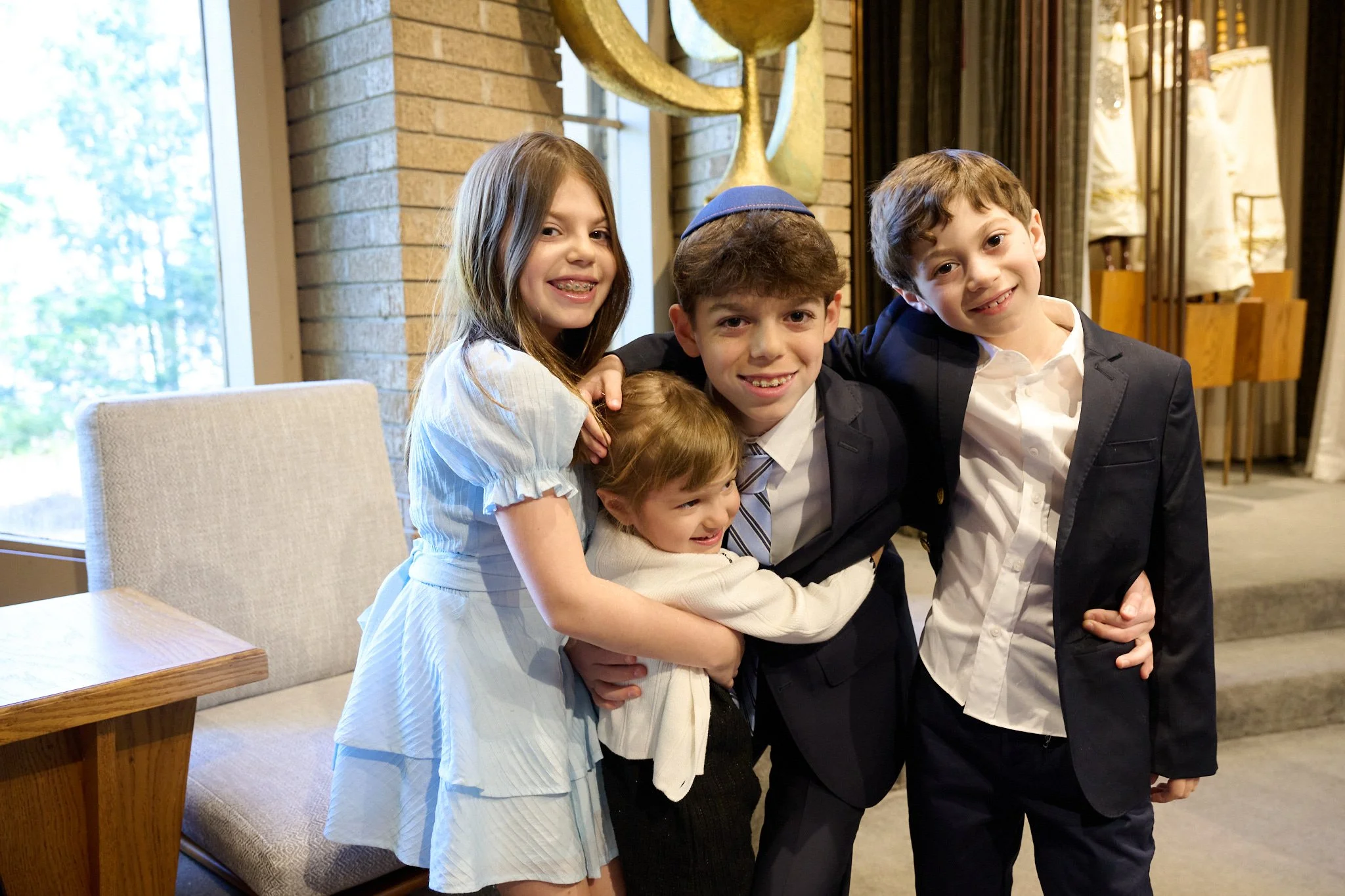 Cousins hug before Bar Mitzvah at Temple Israel in Westport, CT by event photographer Pamela Einarsen.