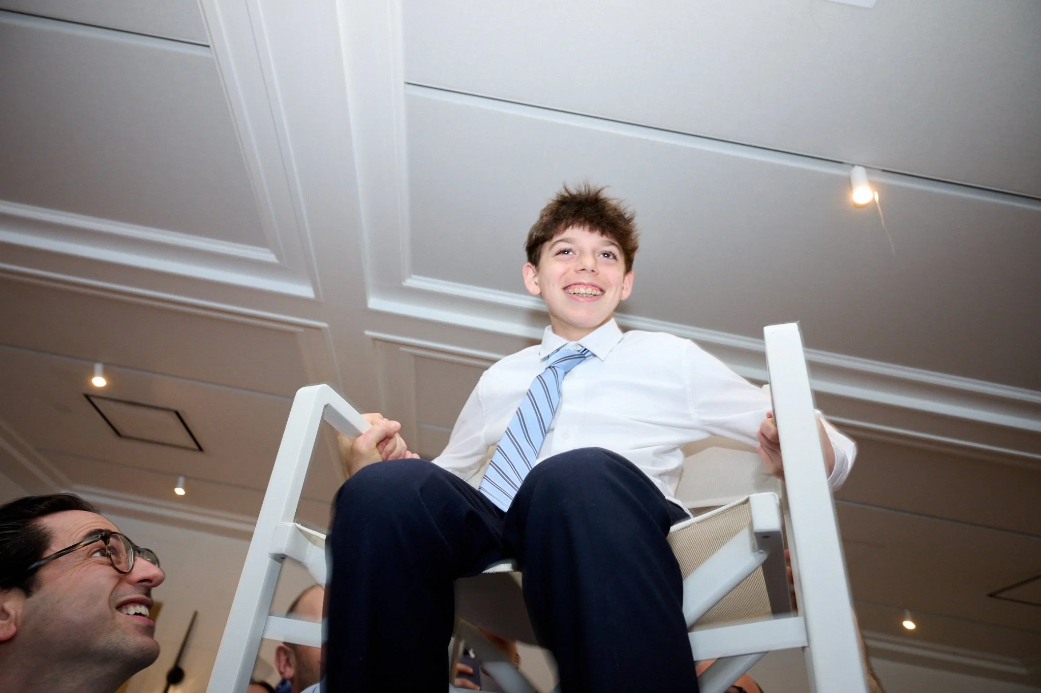 Bar Mitzvah boy lifted up n chair at the Boathouse Restaurant in Westport, CT by event photographer Pamela Einarsen. 