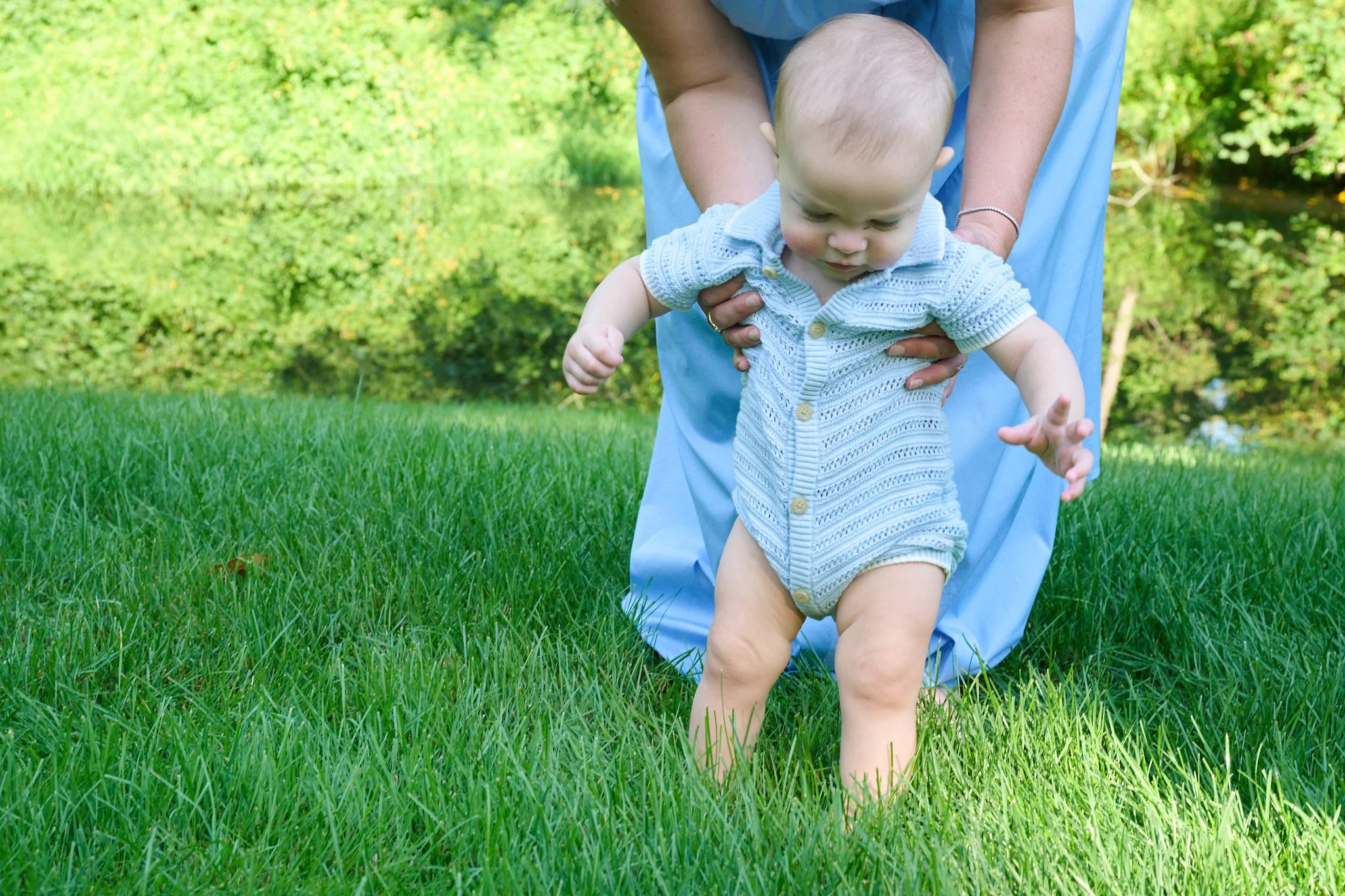 Woman holds a young baby in her Westport CT yard by candid photographer Pamela Einarsen. 