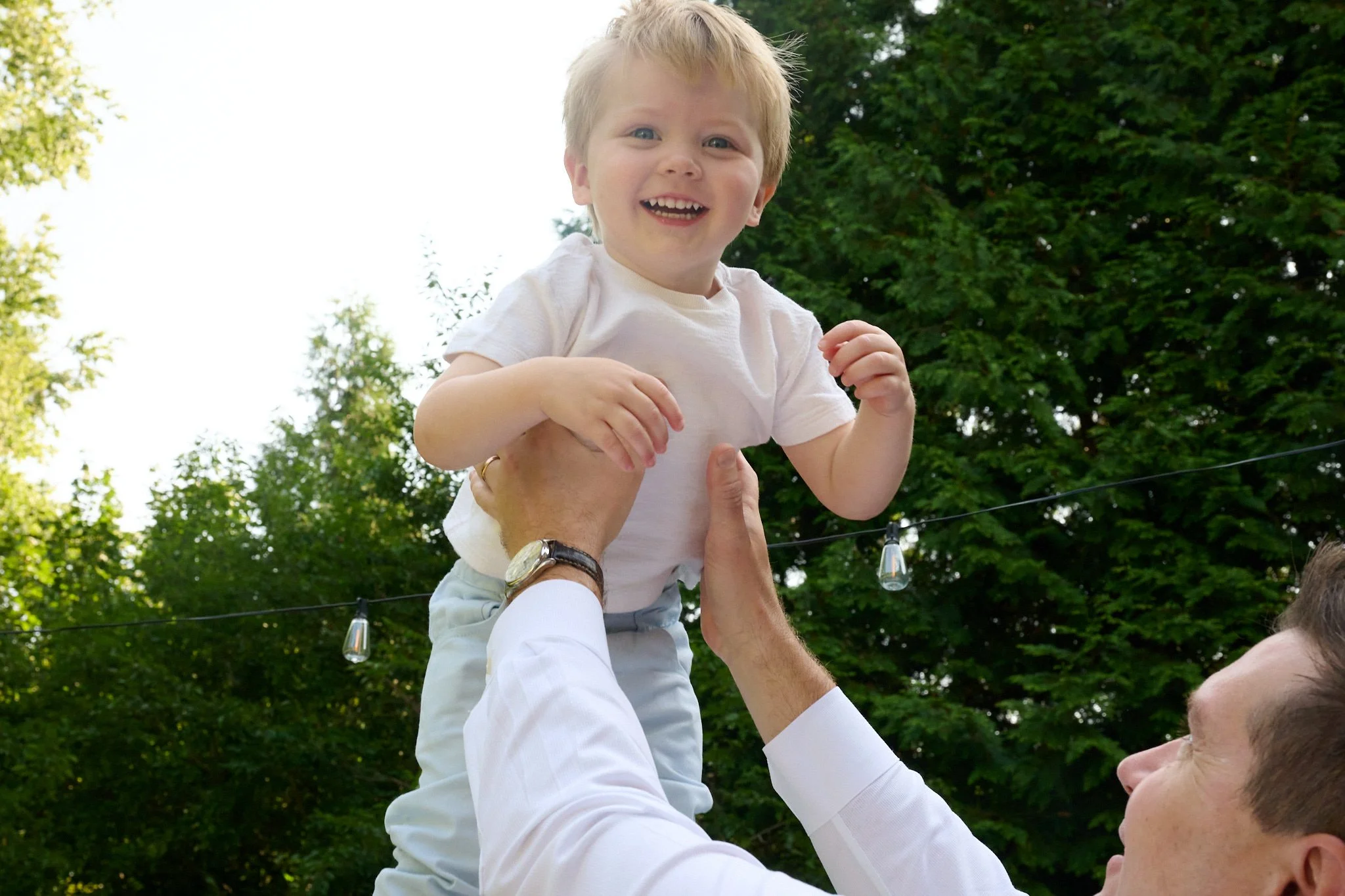Father lifts son up into the air in his Westport, CT yard with family photographer Pamela Einarsen. 