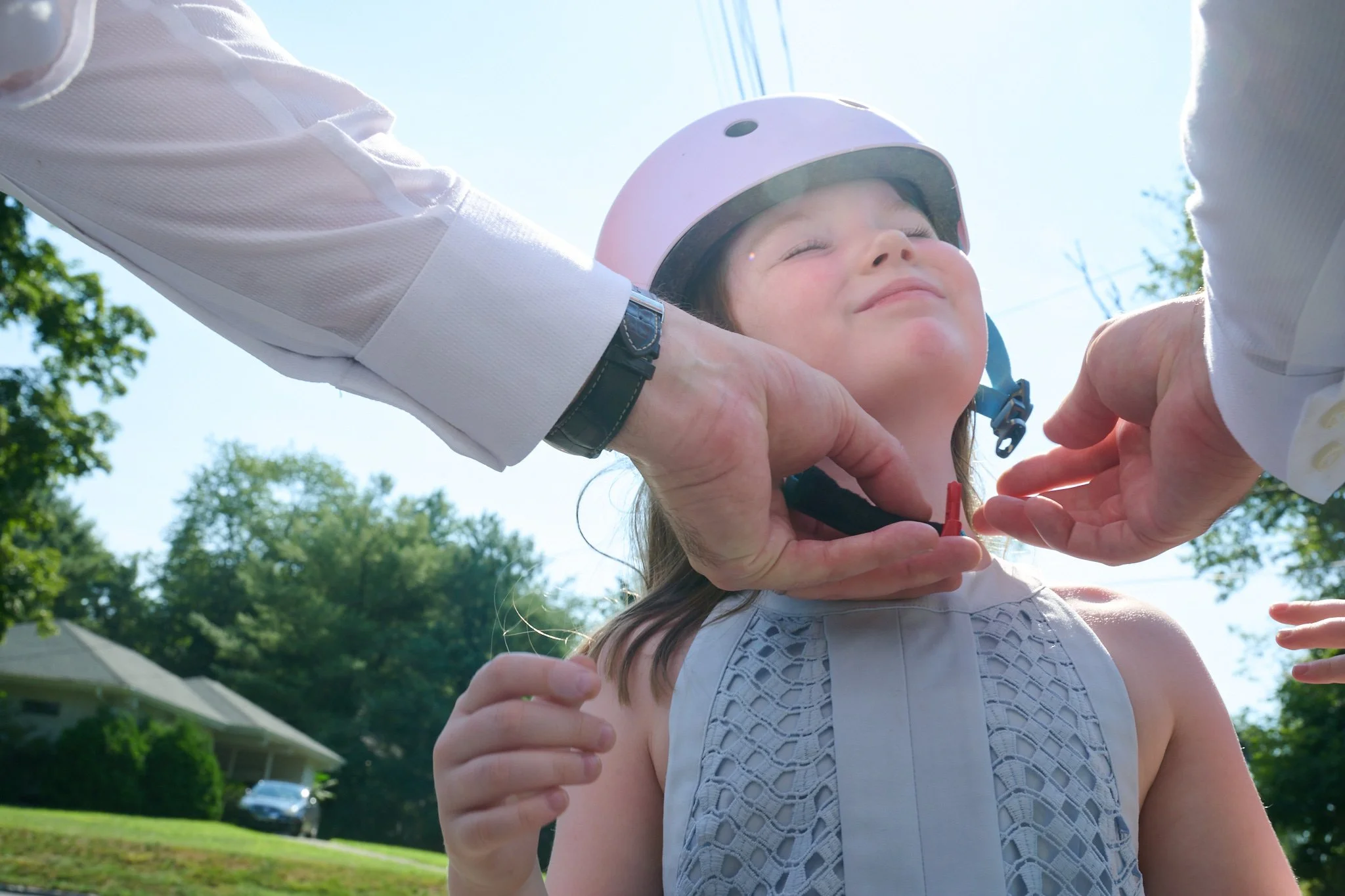 Father puts a bicycle helmet on his daughter in Westport, CT family photo session with photographer Pamela Einrasen. 