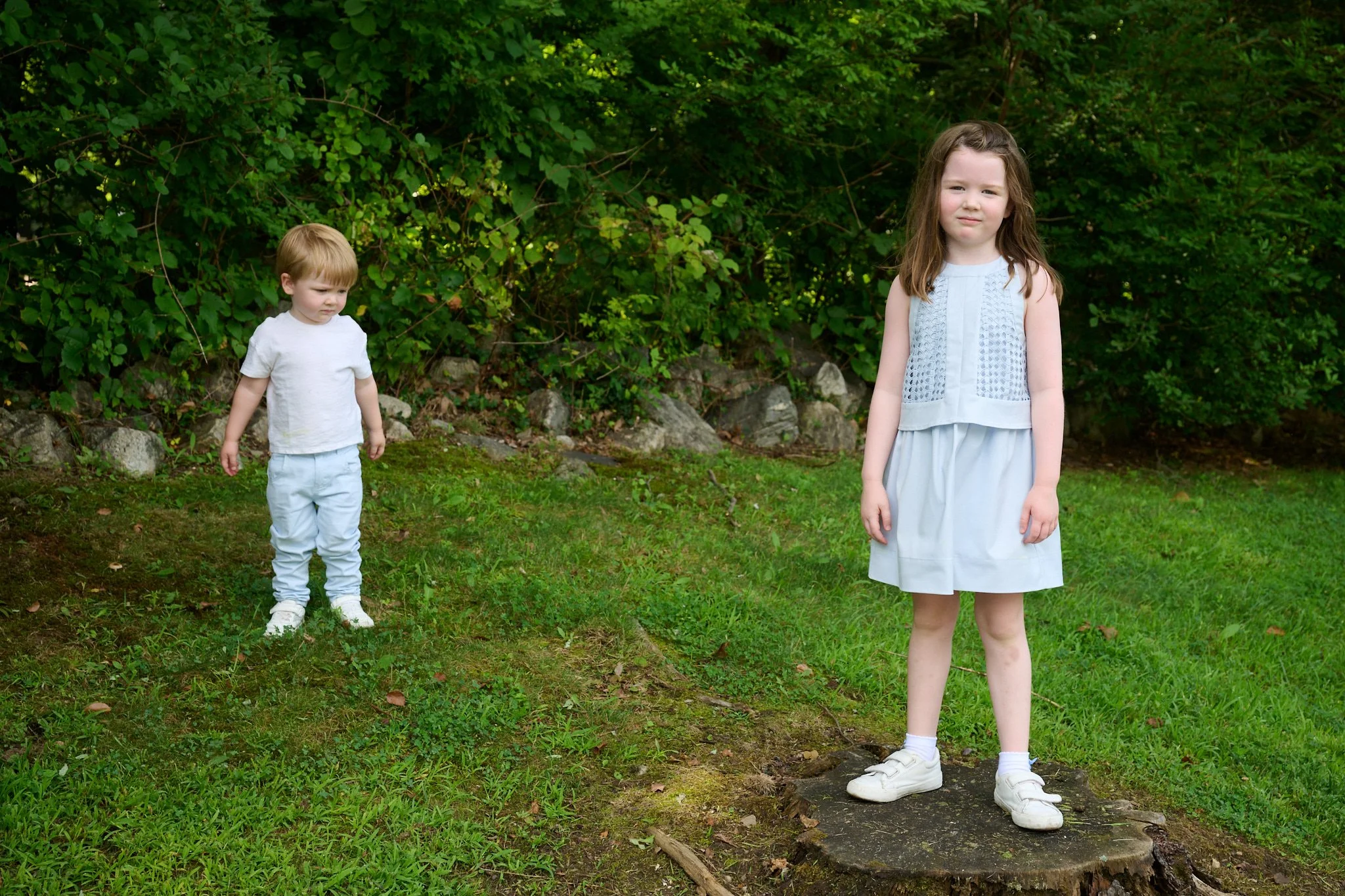 Young girl stands in her yard in Westport CT with her brother for family photographer Pamela Einarsen. 