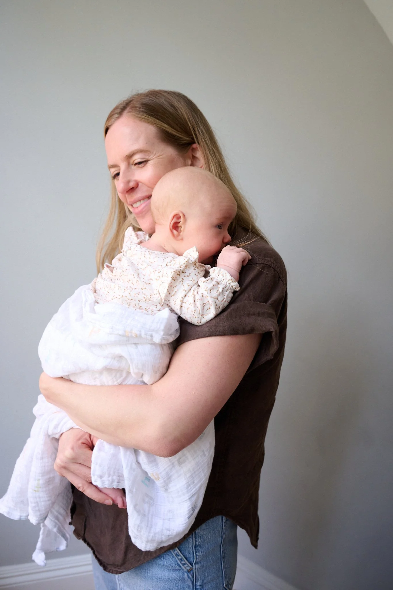 Mom hold newborn daughter in natural light by family photographer Pamela Einarsen.