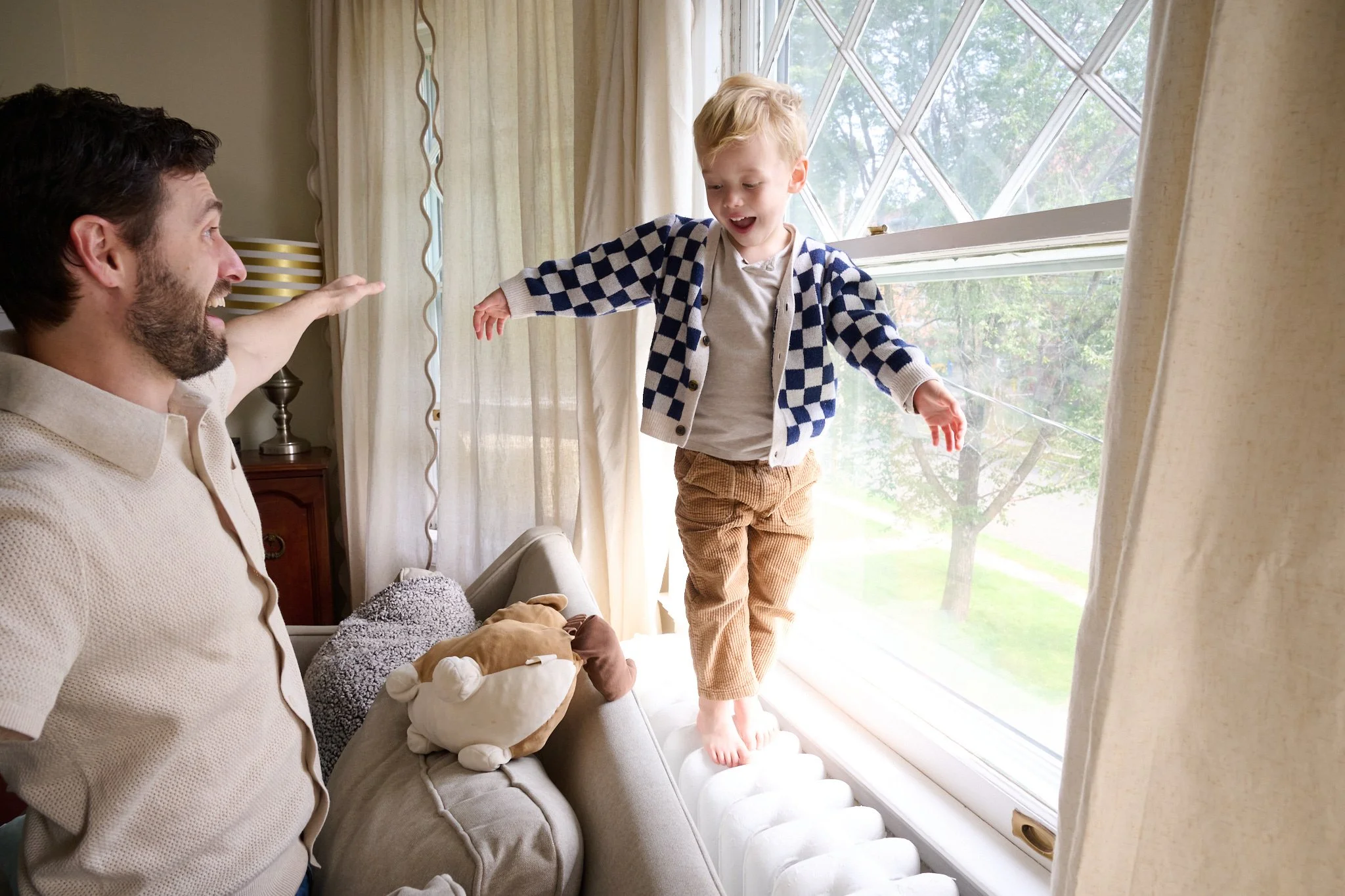 Dad helps son balance by a window in West Hartford, CT by candid photographer Pamela Einarsen. 