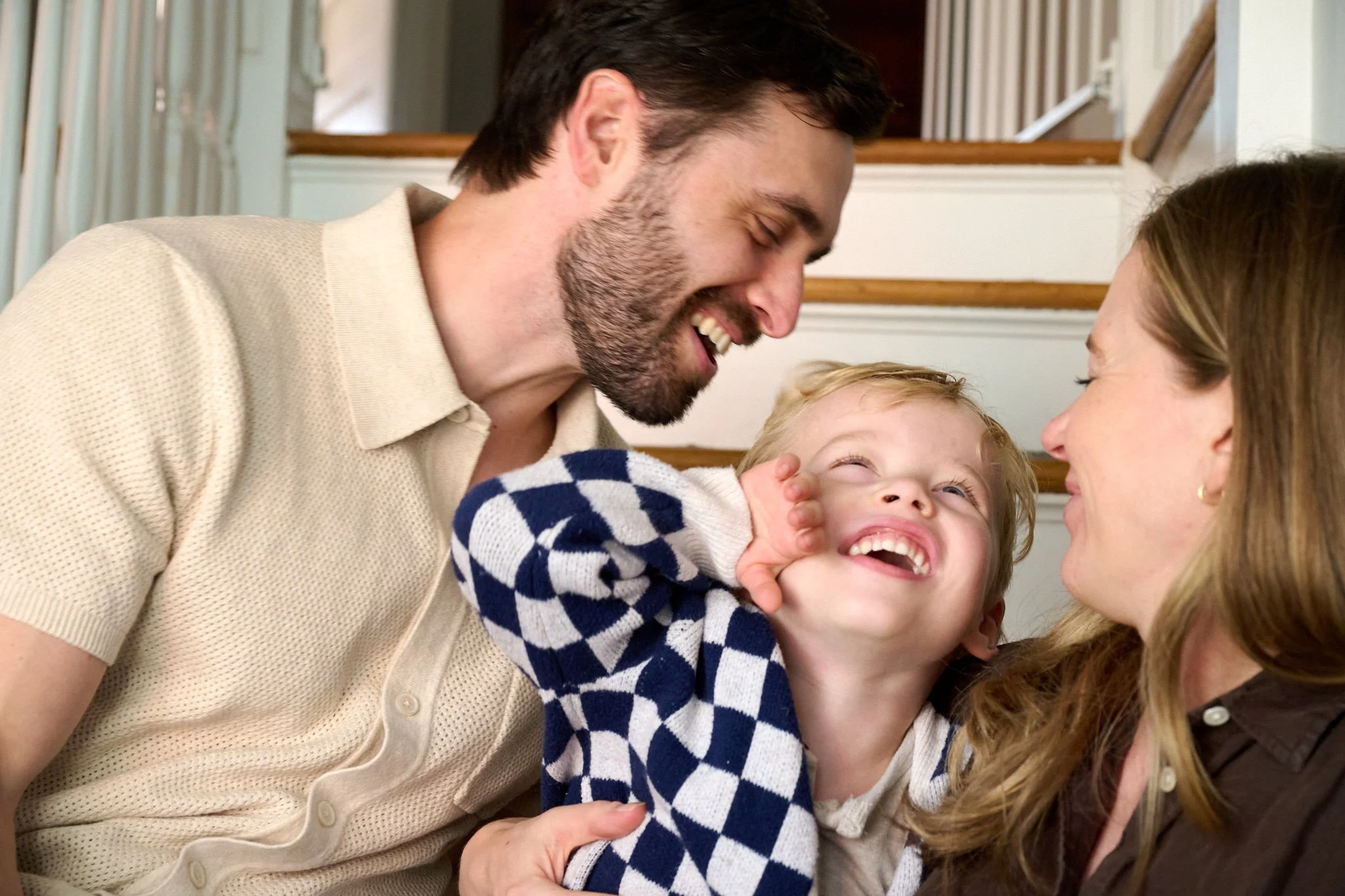 Mom and dad laugh with their son in a candid moment in West Hartford CT by family photographer Pamela Einarsen. 