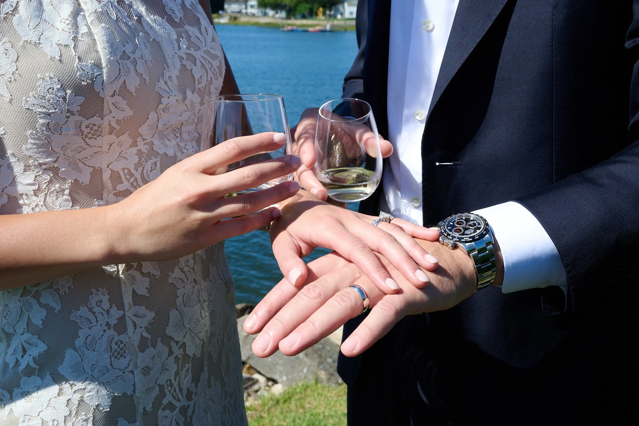 Bride and groom look at their wedding rings as they toast champagne on their lawn in Westport, CT with event photographer Pamela Einarsen.