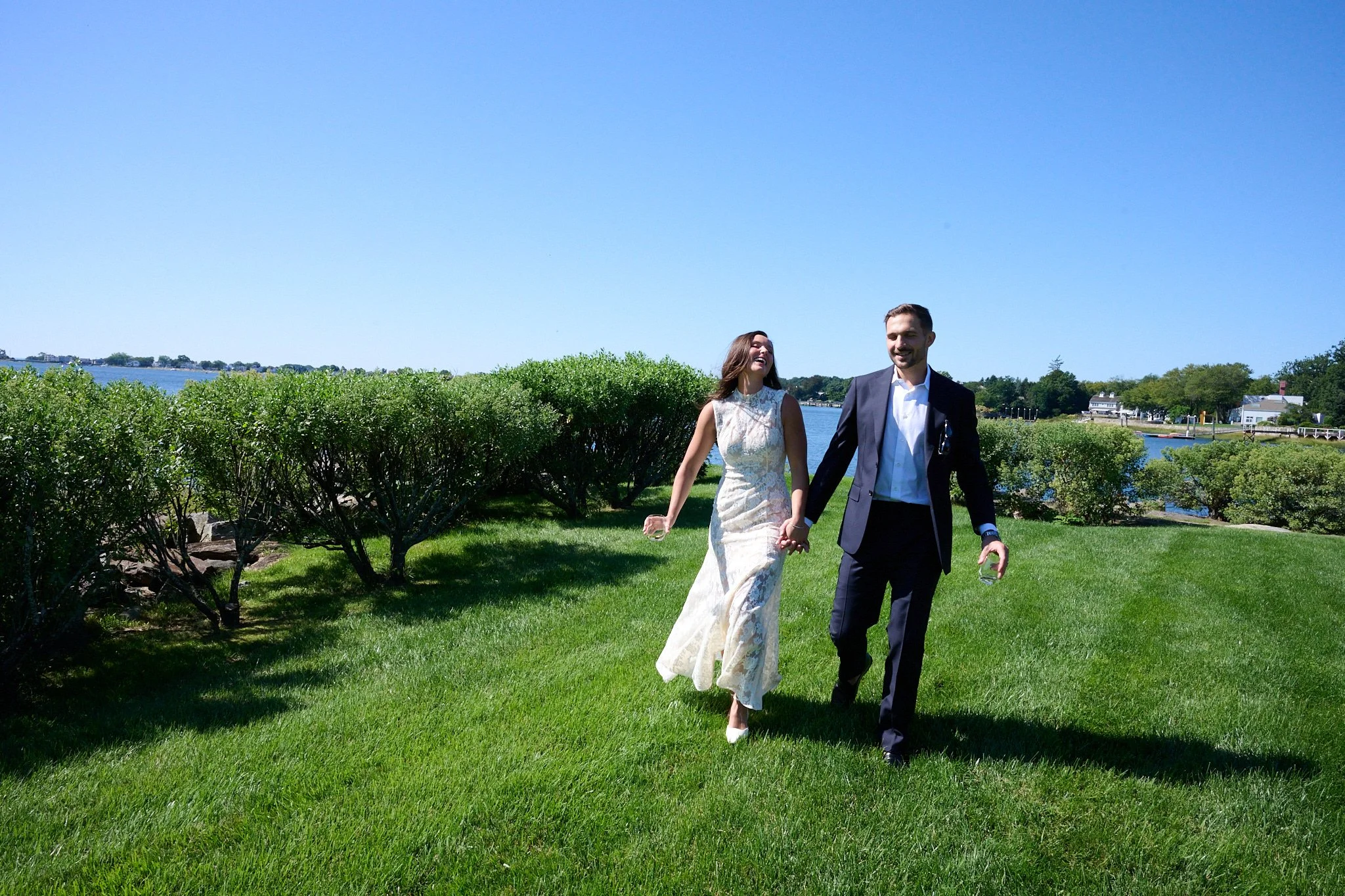 Bride and groom walk across the lawn in Westport CT with wedding photographer Pamela Einarsen. 