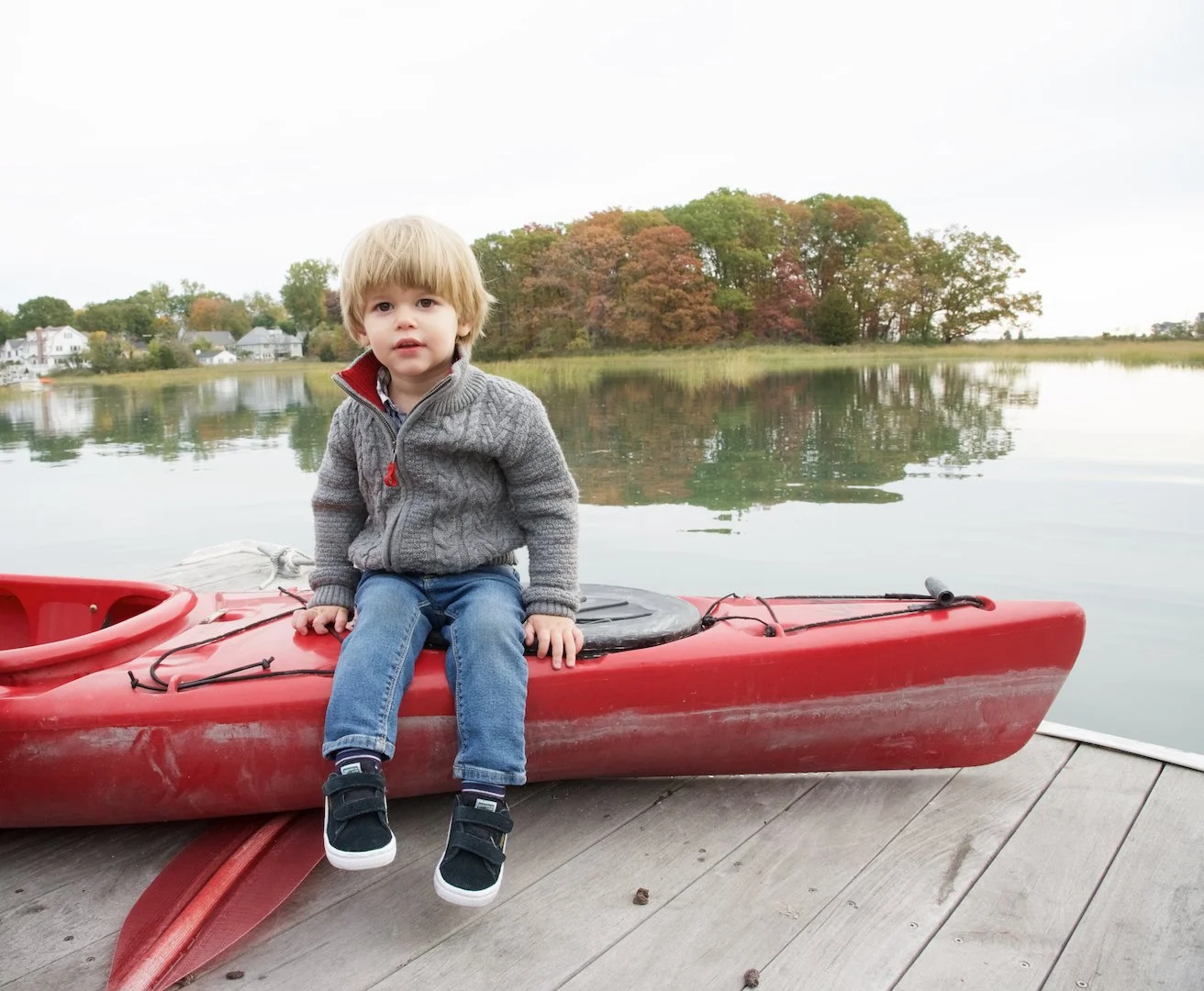 Young boy sits on a kayak in Rowayton posed by photographer