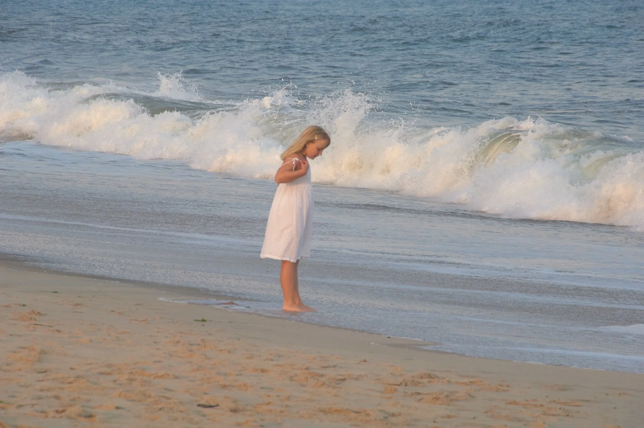 Girl stands by waves in the Hamptons