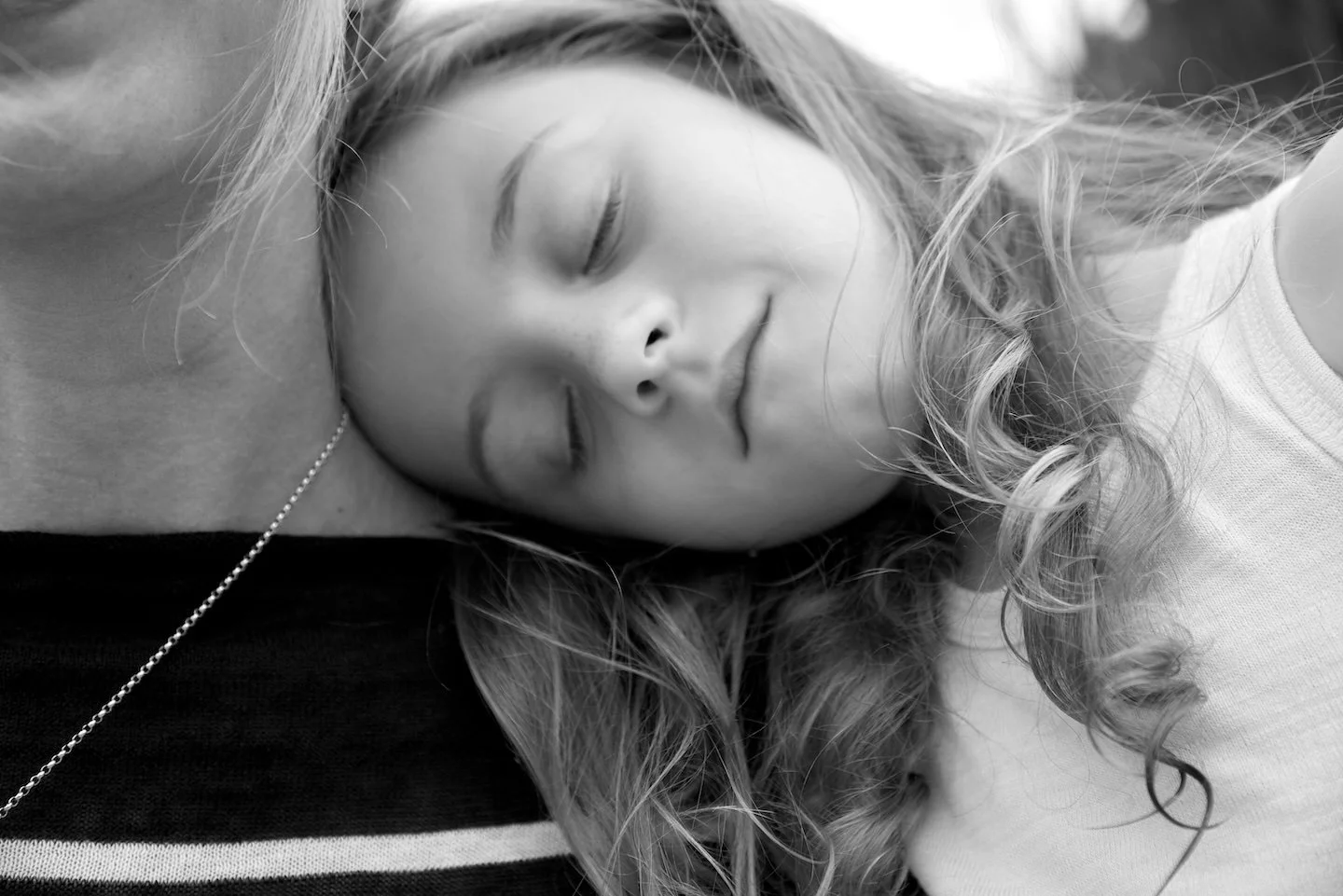 Girl rest her head on mother's shoulder in a B&W photo by photographer Pamela Einarsen in Old Greenwich, Connecticut