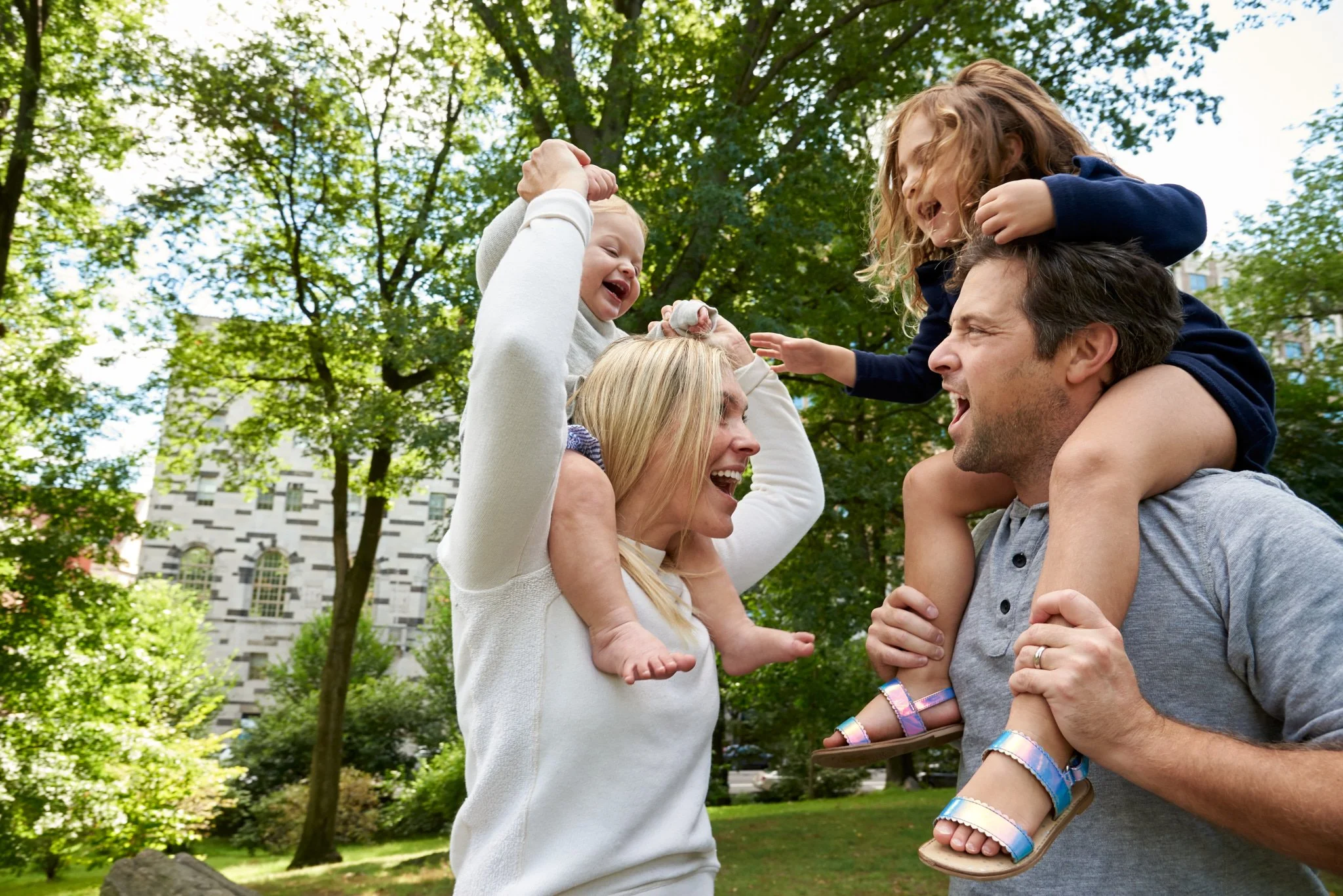 NYC parents with young kids on their should laugh in Central Park with candid photographer