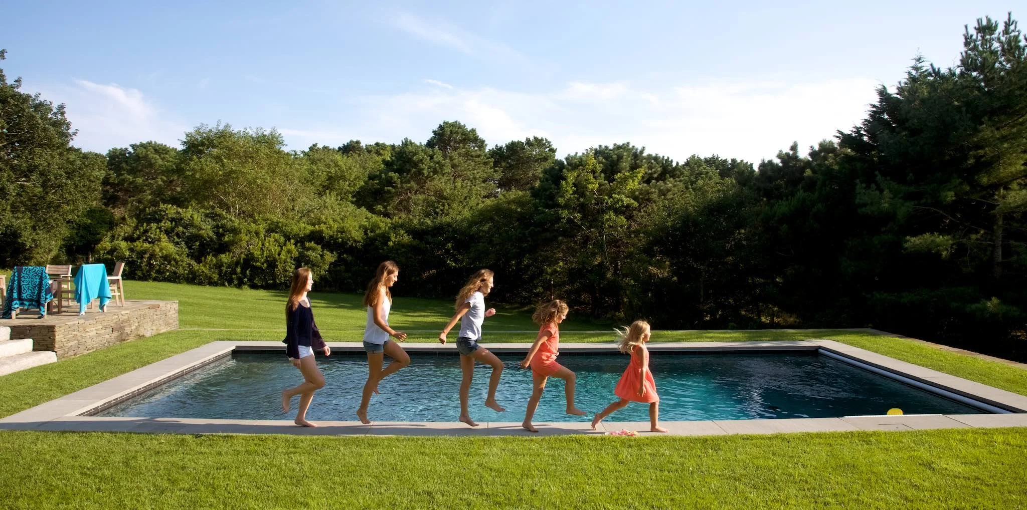 Girls walk along the pool in Nantucket, in a family photo session by lifestyle photographer Pamela Einarsen.