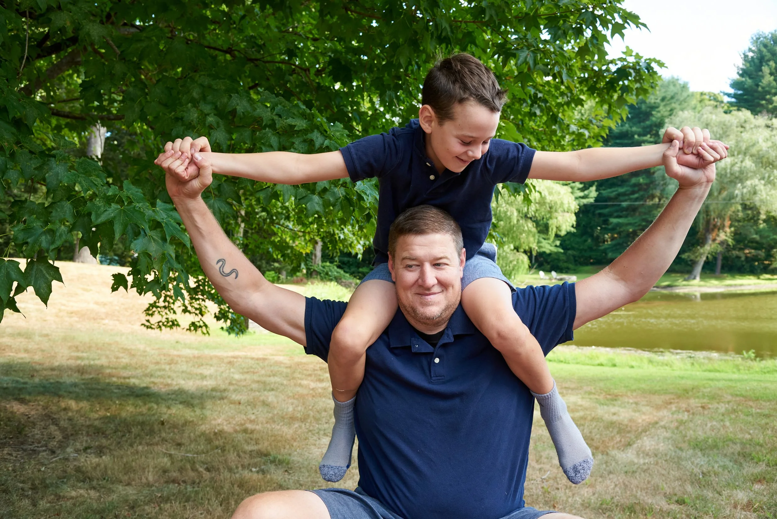 Father carries child on his shoulders through an orchard in Easton — one of the towns Pamela Einarsen photographs across Fairfield County