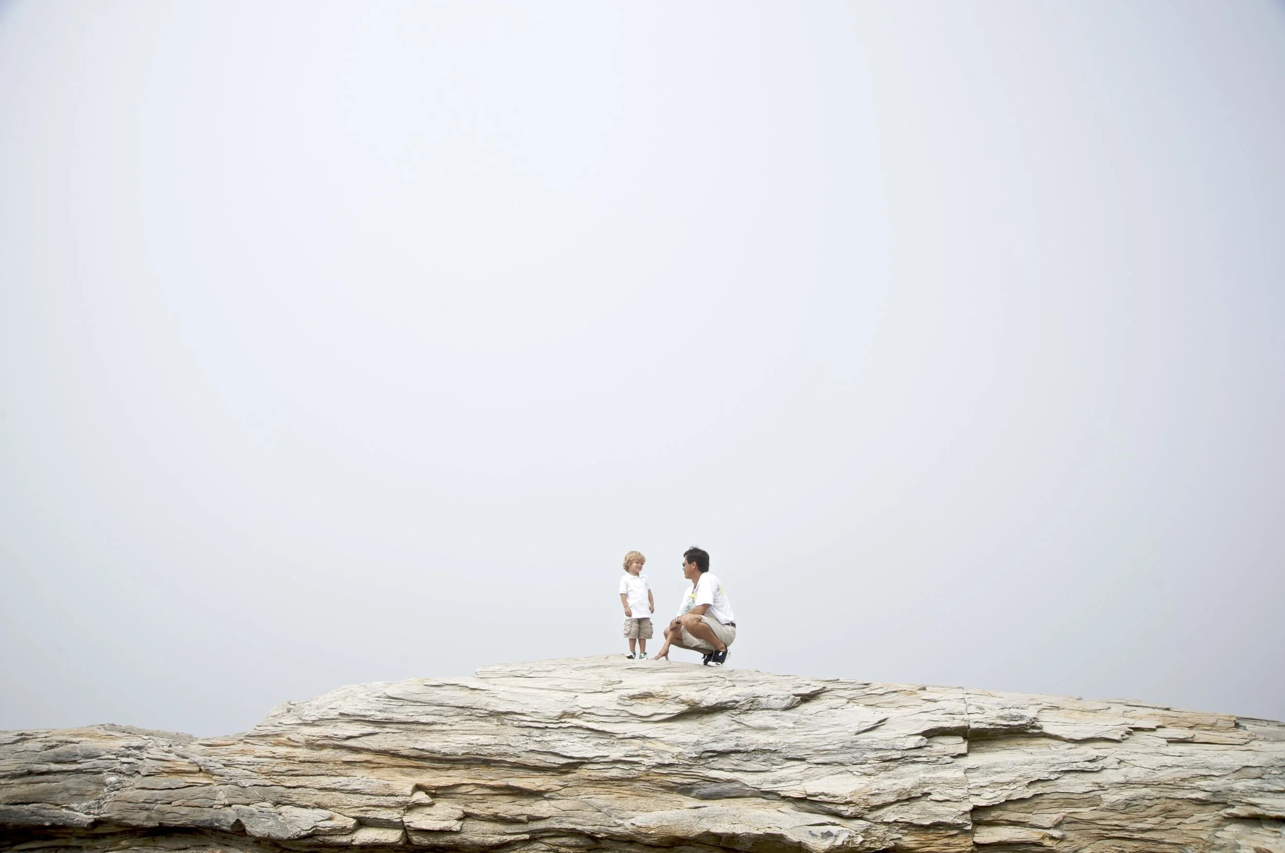 Father and son climb rocks at Narragansett beach