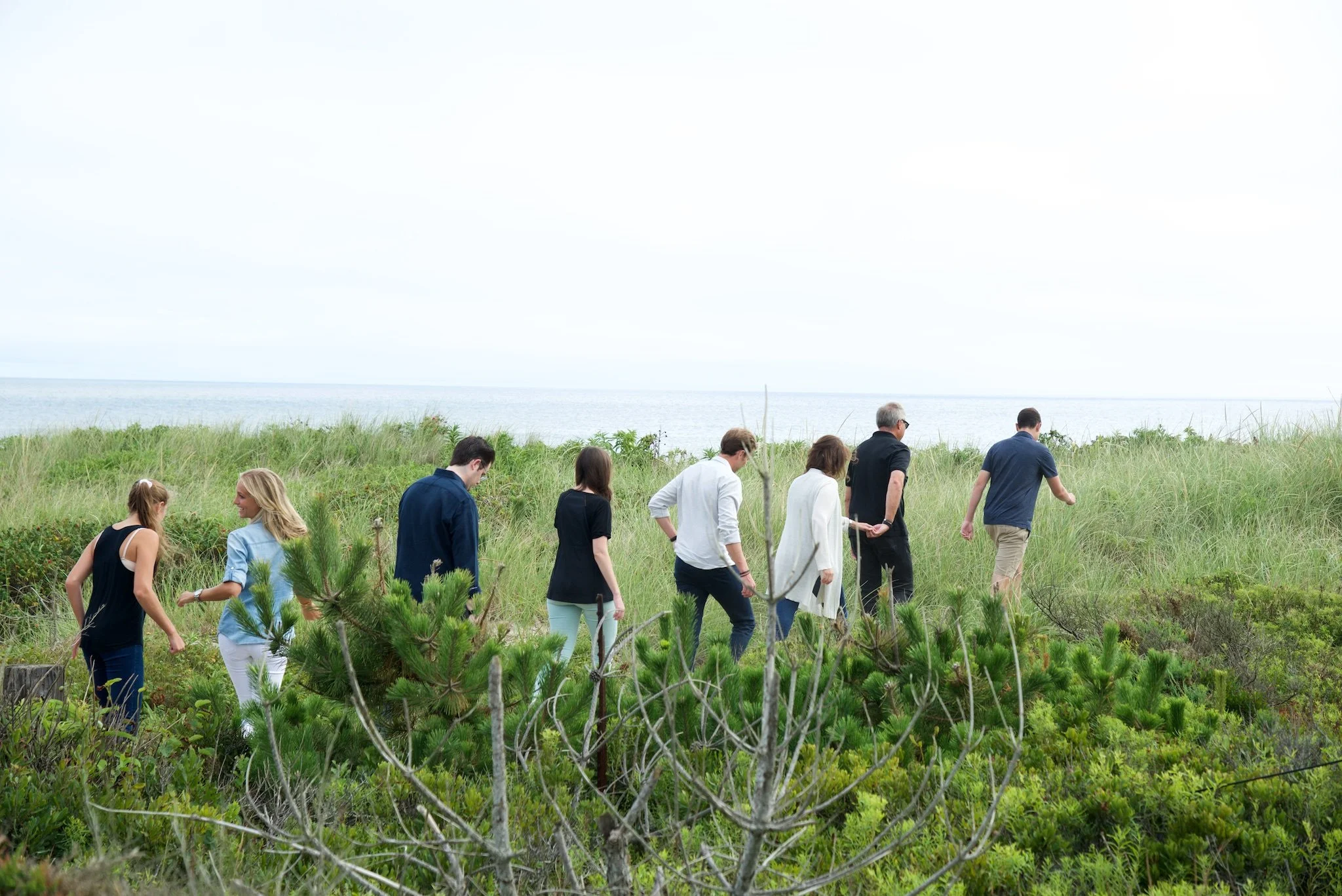An extended family walks across beach dunes at with photographer Pamela Einarsen for a photo session on Nantucket