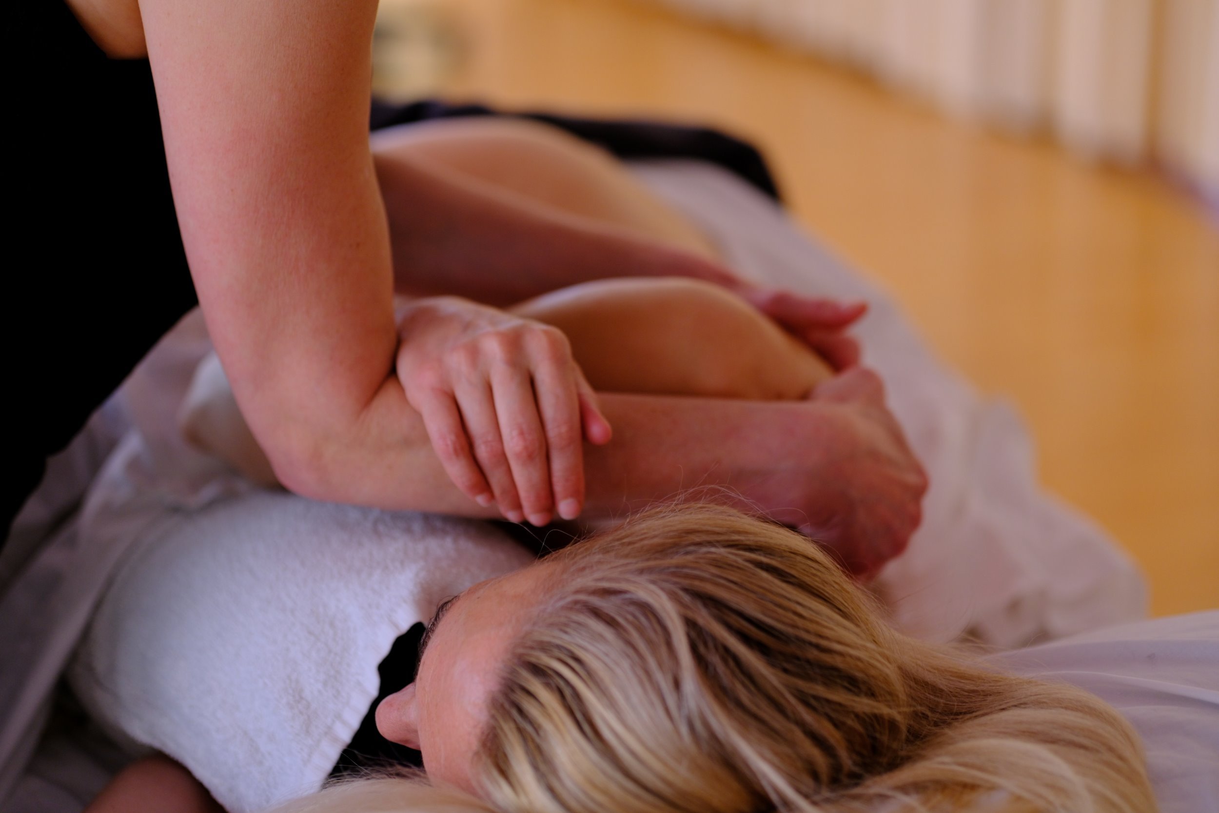 In einer Esalen® Massage-Fortbildung wird eine Massagetechnik am Schulterbereich geübt.