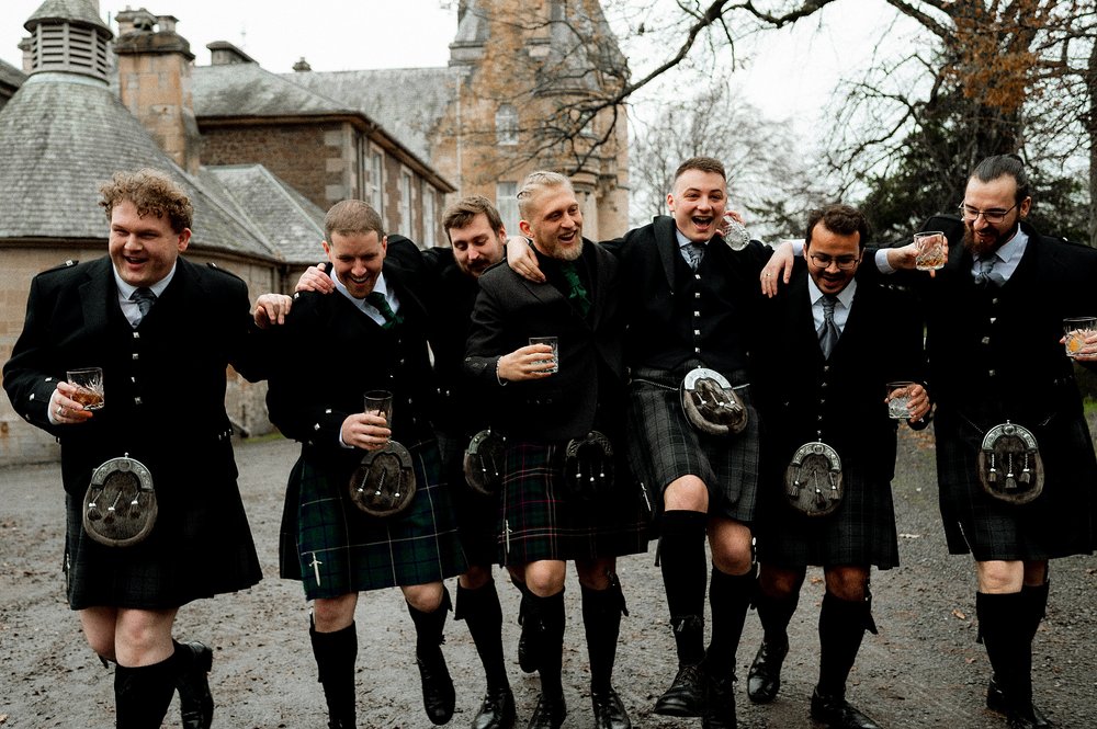 the groom and groomsmen wearing traditional scottish attire assemble before the wedding ceremony organised by an american destination wedding planner glasgow 