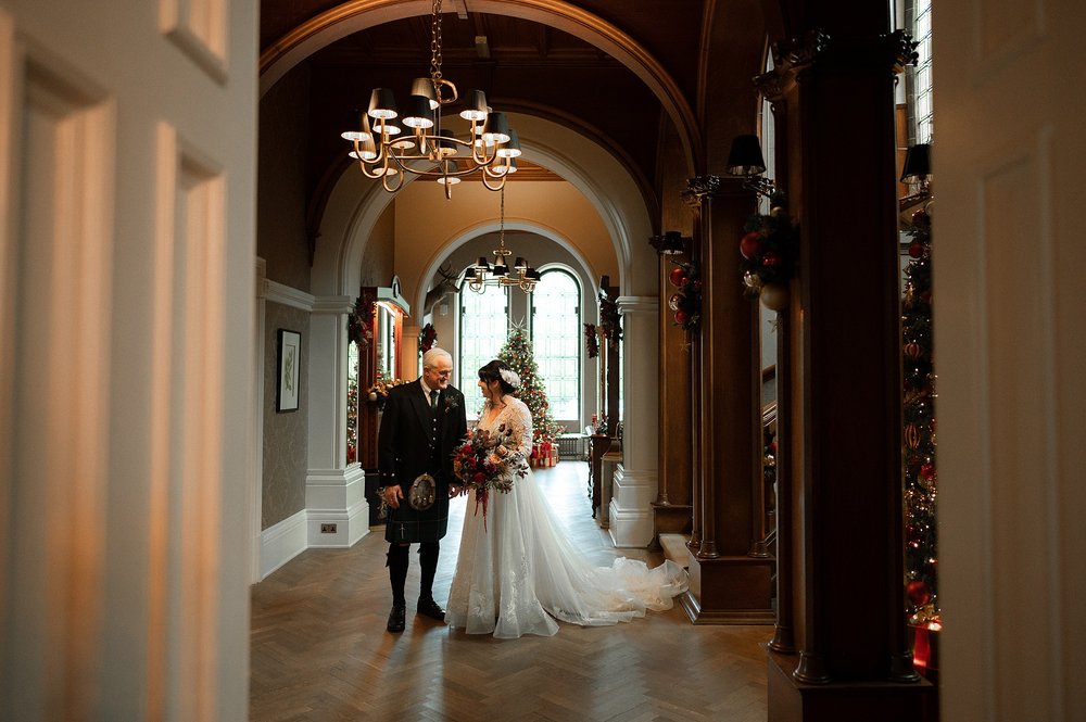 the bride and father of the bride prepare to walk down the aisle before the wedding ceremony organised by an american destination wedding planner in glasgow scotland