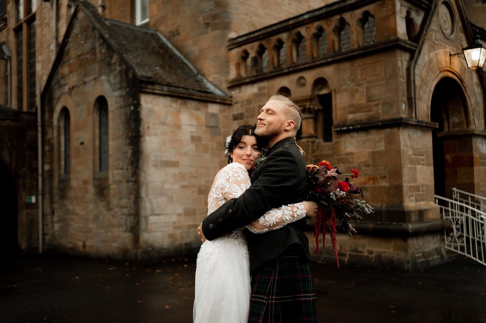 the bride and groom embrace outside cornhill castle wedding venue in biggar in lanarkshire scotland