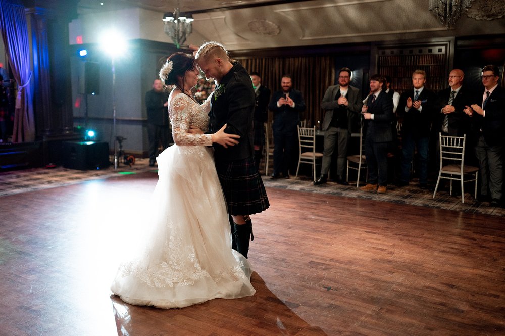 the bride and groom perform their first dance as guests look on during their reception organised by an american destination wedding planner in glasgow