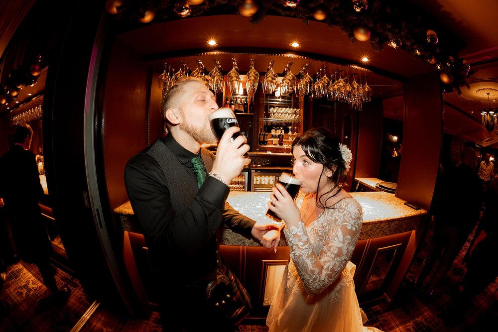 the bride and groom drink pints of guinness at the bar following their cornhill castle wedding in biggar scotland