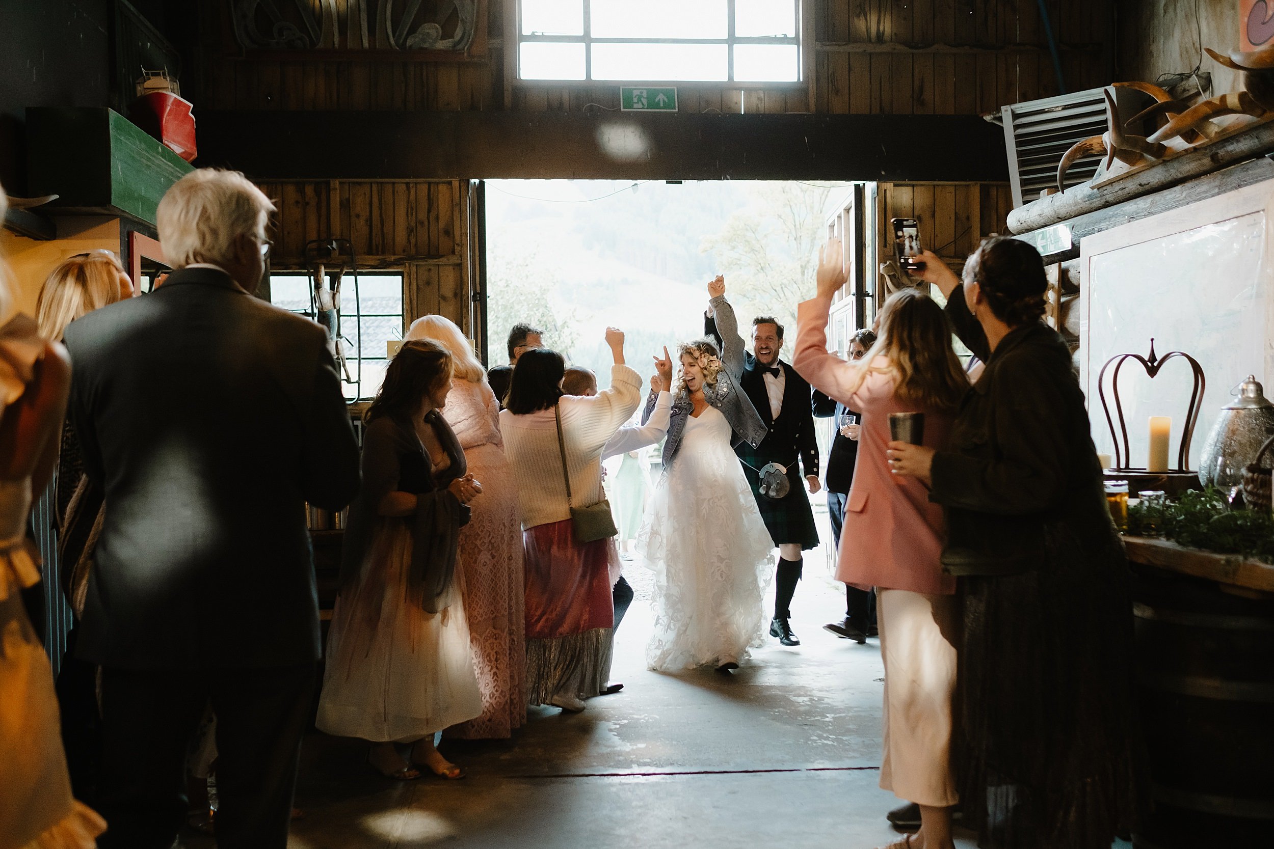 guests cheer as the bride and groom arrive for their first dance at monachyle mhor wedding venue in perthshire in scotland