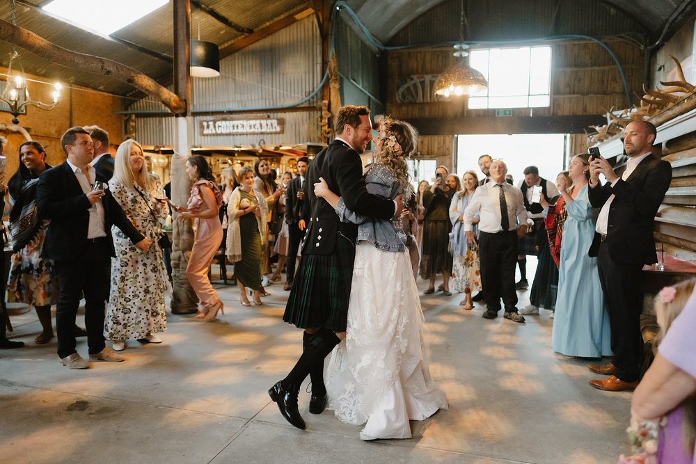 guests watch as the bride and groom share their first dance in a barn at Monachyle Mhor wedding venue in perthshire in scotland