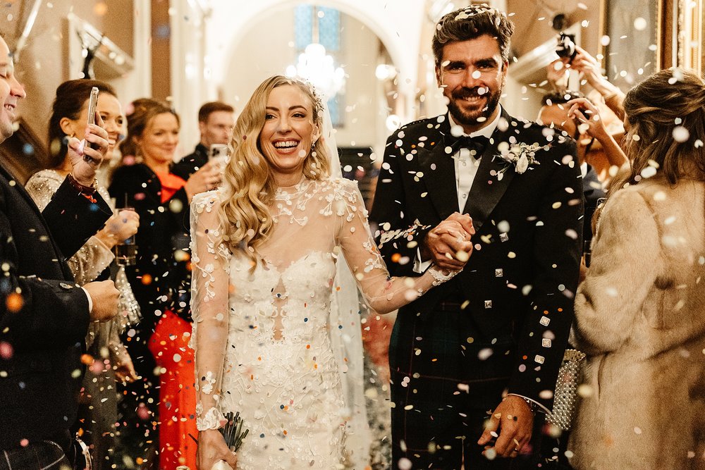 bride and groom under confetti throw inside drumtochty castle after their ceremony by Scottish destination wedding planner