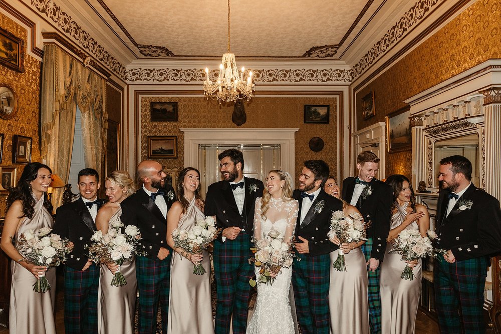 bridal party standing together for a photograph during a stylish wedding inside drumtochty castle planned by a Scottish destination wedding planner