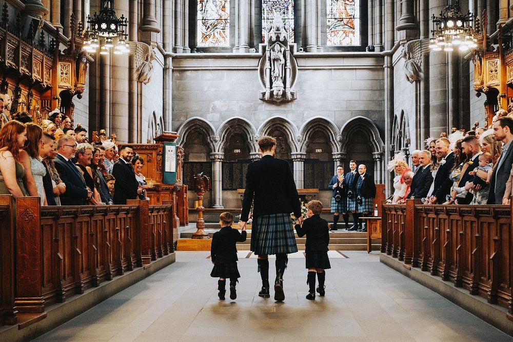 groom walking down the aisle at glasgow university memorial chapel before the couple's diy wedding venue scotland reception at barrowlands