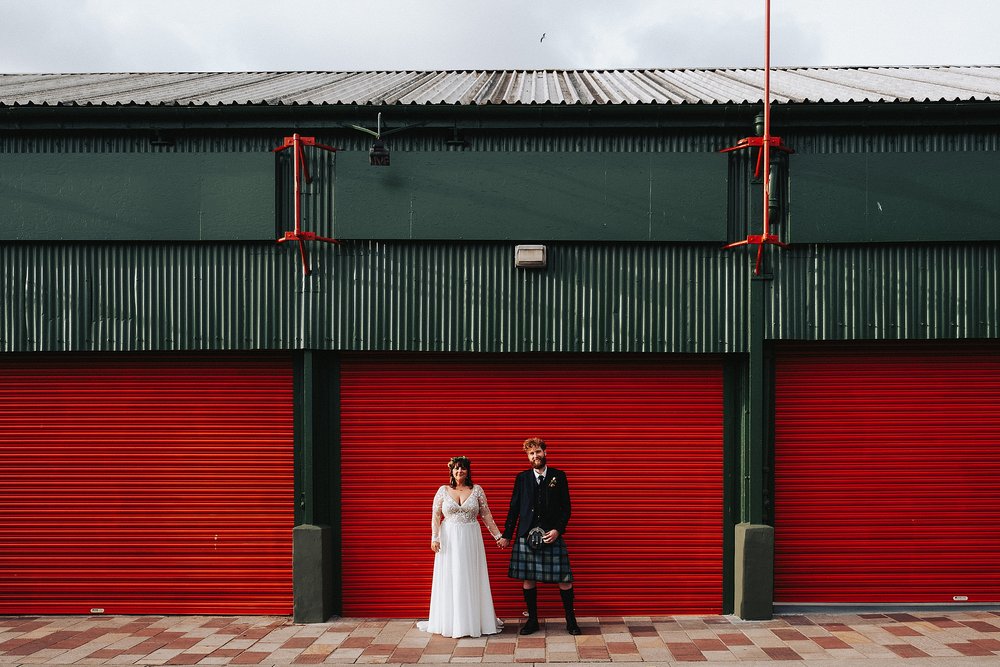 bride and groom standing outside the barras glasgow during their wedding reception at glasgow barrowland