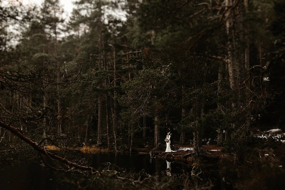 bride and groom standing on the shore of a loch in the cairngorms during their elopement by Scottish highlands destination wedding planner