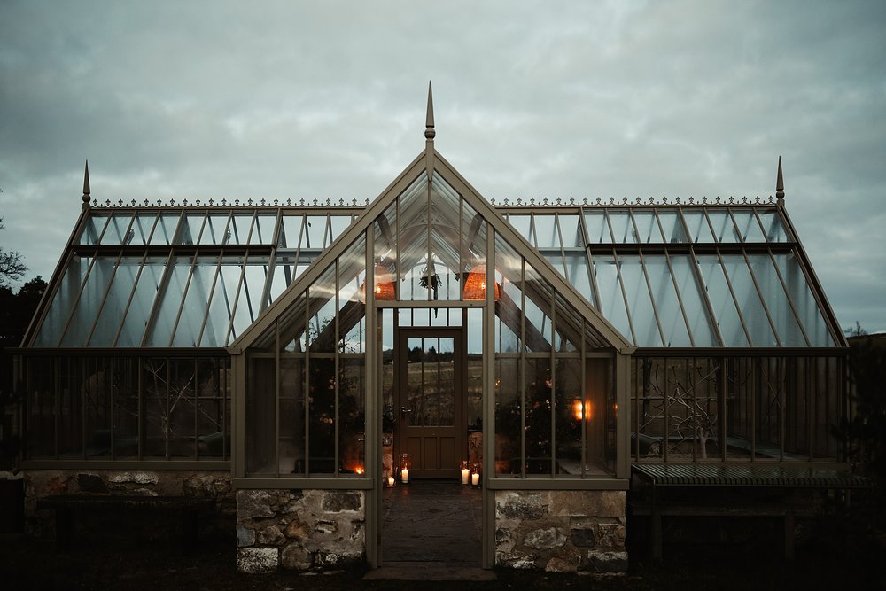 the glasshouse at Geordie's cottage killiehuntly at dusk lit up with candles and decorated with flowers for a wedding by Scottish elopement planner