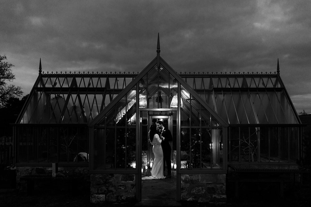 bride and groom during their first dance in a glasshouse at killiehuntly at dusk in candlelight for their elopement by Scottish highlands destination wedding planner