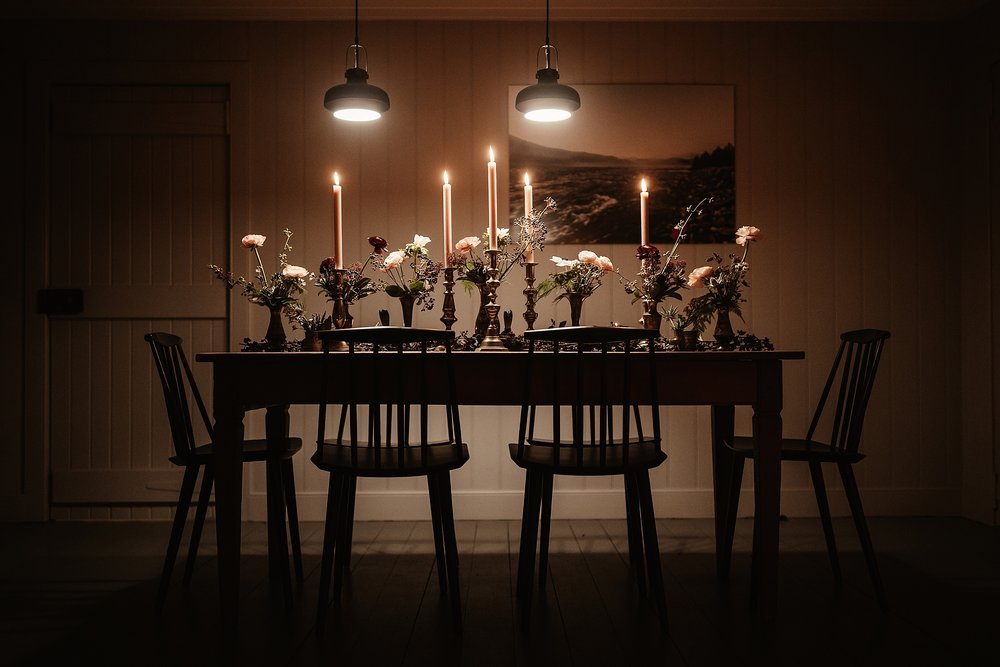 a stunning tablescape of flowers and candles in a darkened room lit by overhead lamps for an elopement celebration by Scottish highlands destination wedding planner