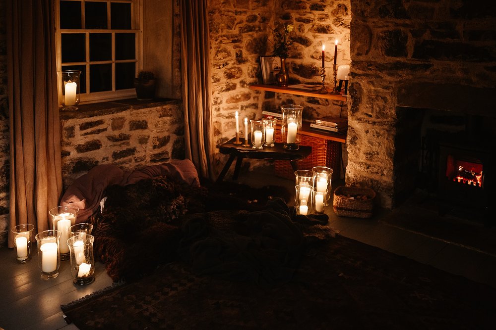 a cosy corner with blankets and candles by the fire in a Scottish cottage on the evening of a Scottish elopement