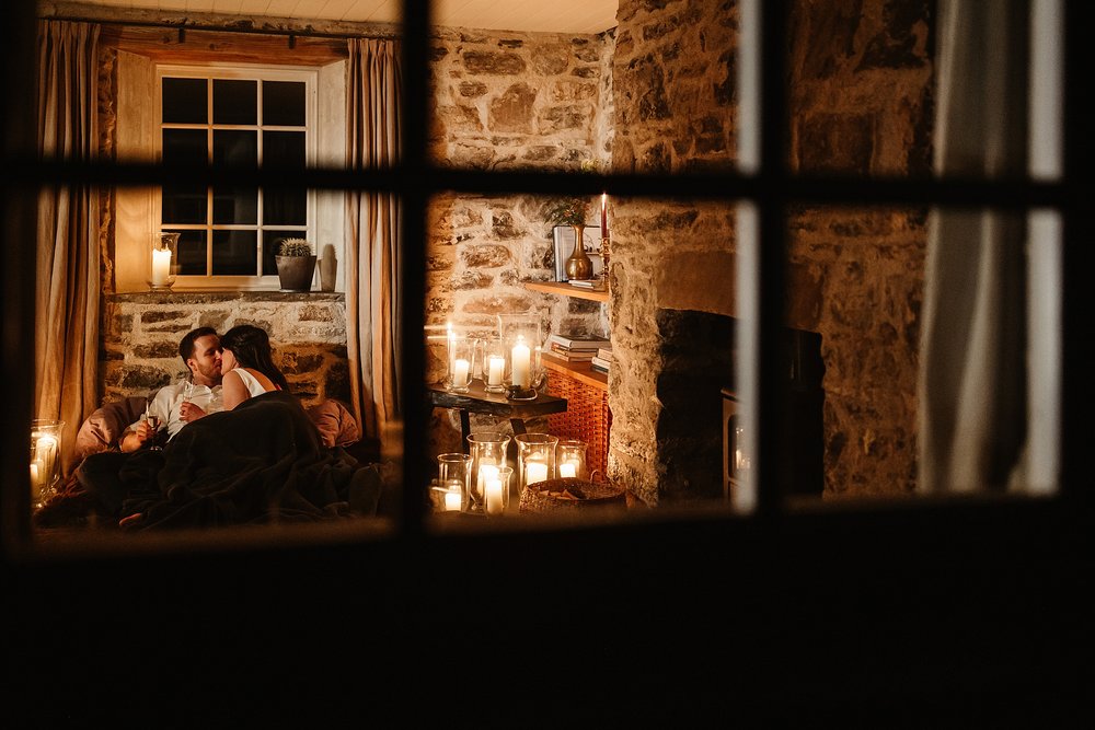 newlyweds cosied up in blankets by the fire in candlelight on the evening of their elopement by Scottish highlands destination wedding planner