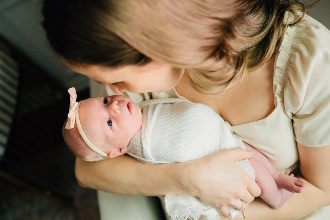    Travelers Rest in home newborn photographers capturing baby Charley with her parents in her nursery    Baby girl newborn photos with parents in a Travelers Rest SC nursery    Mom holding swaddled newborn baby girl beside an antique brass crib in T