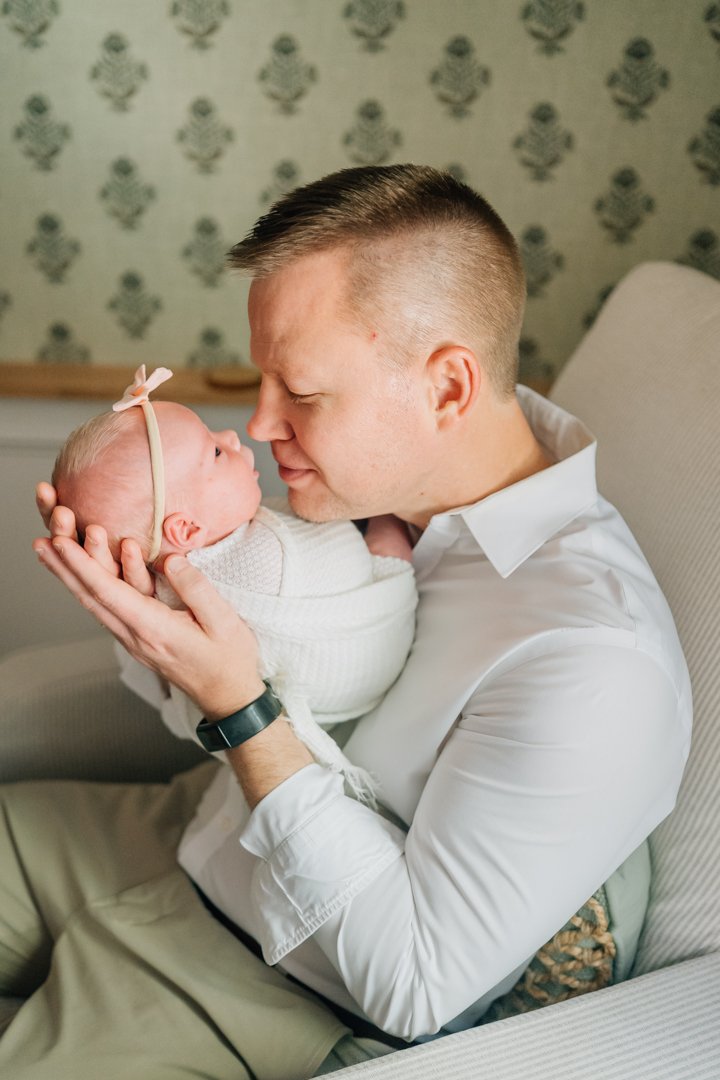    Travelers Rest in home newborn photographers capturing baby Charley with her parents in her nursery    Baby girl newborn photos with parents in a Travelers Rest SC nursery    Mom holding swaddled newborn baby girl beside an antique brass crib in T