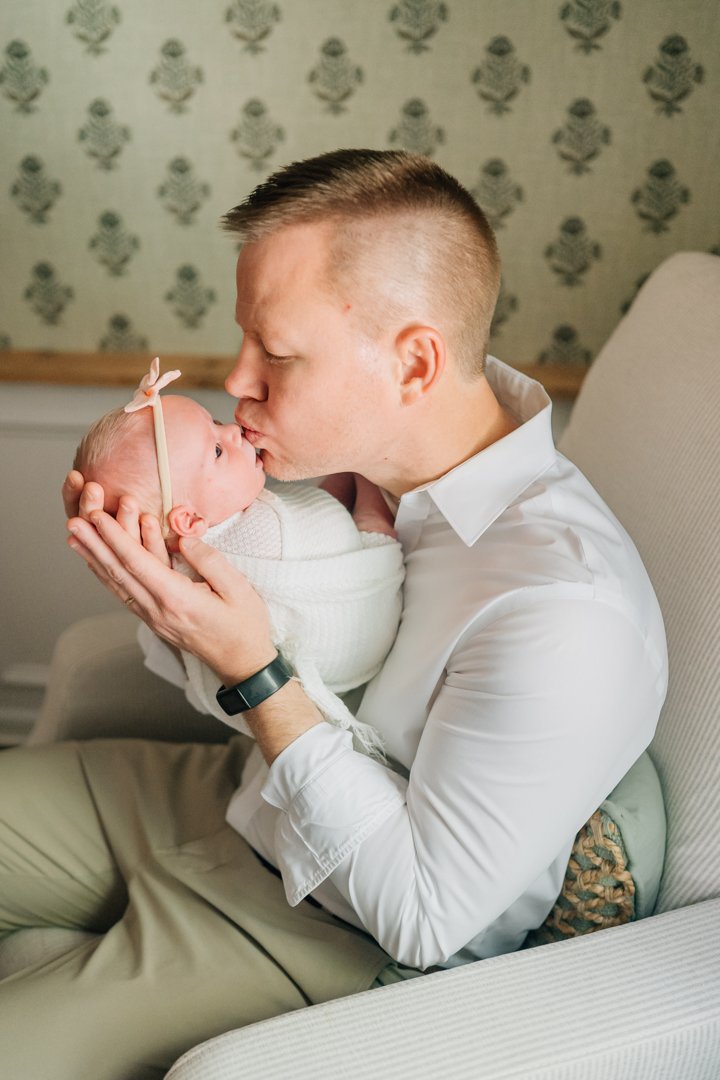    Travelers Rest in home newborn photographers capturing baby Charley with her parents in her nursery    Baby girl newborn photos with parents in a Travelers Rest SC nursery    Mom holding swaddled newborn baby girl beside an antique brass crib in T