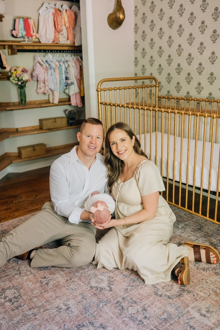    Travelers Rest in home newborn photographers capturing baby Charley with her parents in her nursery    Baby girl newborn photos with parents in a Travelers Rest SC nursery    Mom holding swaddled newborn baby girl beside an antique brass crib in T