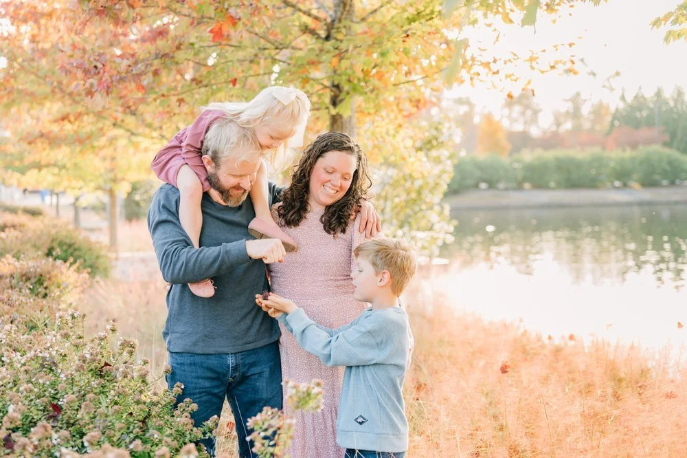 Family of four at a lakeside park during autumn.