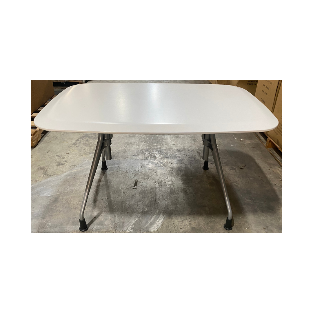 Side view of the Herman Miller Avive table featuring a smooth white laminate top and four splayed silver metal legs with black floor glides