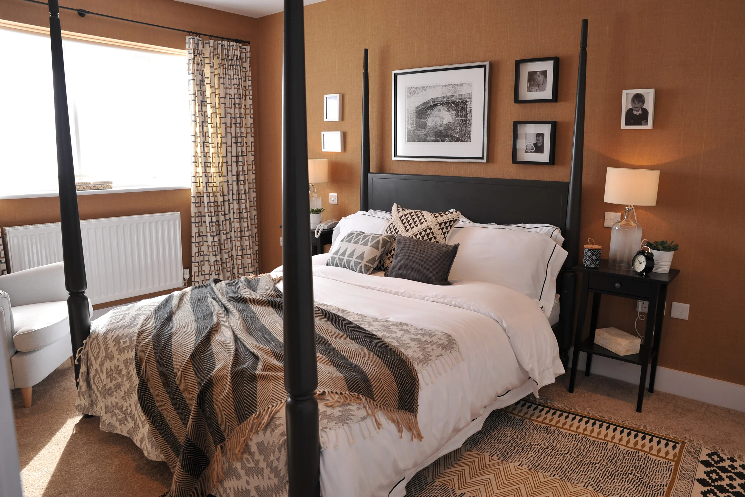 Master bedroom with hessian wallpaper and a charcoal four poster bed.