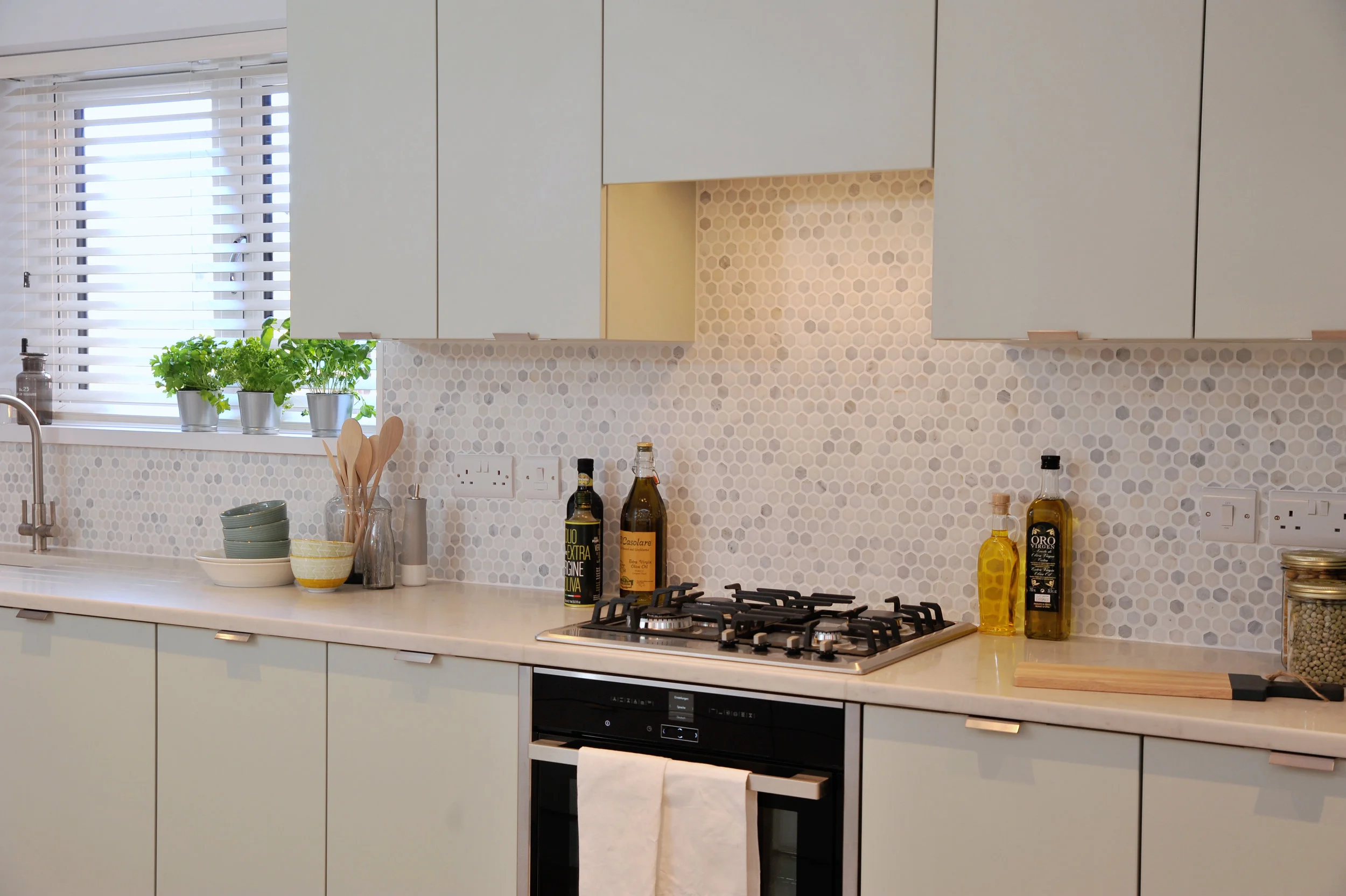 Mint green kitchen with hexagonal marble tiles and marble worktop.